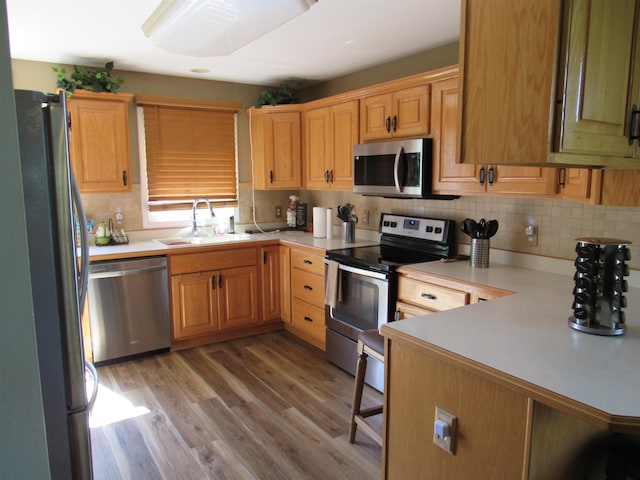 6044 Belmont Ct, Grand Blanc, MI 48439 - kitchen with stainless steel appliances, a sink, a peninsula, light countertops, and backsplash