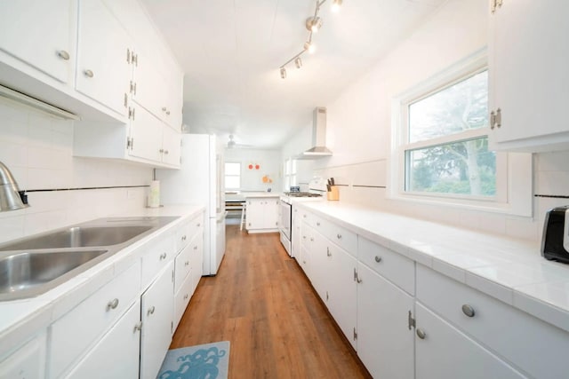 724 Wilson St, South Haven, MI 49090 - kitchen featuring white appliances, a sink, wall chimney exhaust hood, white cabinetry, and light wood-style flooring