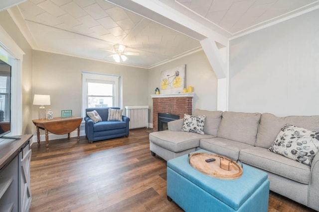 724 Wilson St, South Haven, MI 49090 - living area with ornamental molding, radiator heating unit, dark wood-style flooring, a brick fireplace, and ceiling fan