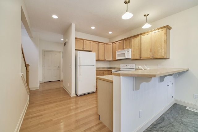 70 Spinnaker Dr, Manistee, MI 49660 - kitchen featuring white appliances, a peninsula, a kitchen bar, light wood-style floors, and light countertops