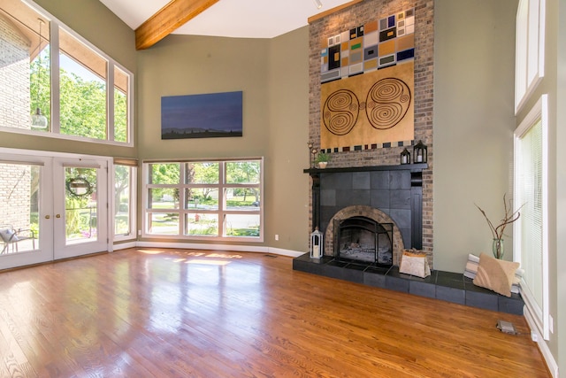 3007 Cedarbrook Rd, Ann Arbor, MI 48105 - unfurnished living room featuring a high ceiling, wood finished floors, beam ceiling, a tiled fireplace, and french doors