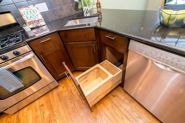 3007 Cedarbrook Rd, Ann Arbor, MI 48105 - kitchen featuring dishwasher, a sink, light wood-style flooring, tasteful backsplash, and dark countertops