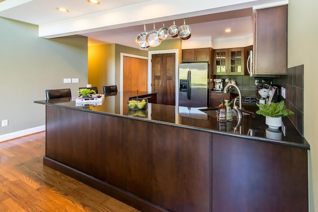 3007 Cedarbrook Rd, Ann Arbor, MI 48105 - kitchen featuring appliances with stainless steel finishes, wood finished floors, a peninsula, tasteful backsplash, and glass insert cabinets