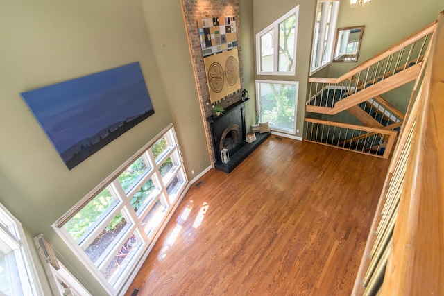 3007 Cedarbrook Rd, Ann Arbor, MI 48105 - unfurnished living room with a towering ceiling, stairway, a fireplace with raised hearth, wood finished floors, and baseboards