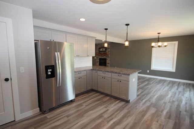 10141 S 33rd St, Vicksburg, MI 49097 - kitchen with stainless steel refrigerator with ice dispenser, a peninsula, backsplash, light wood finished floors, and pendant lighting