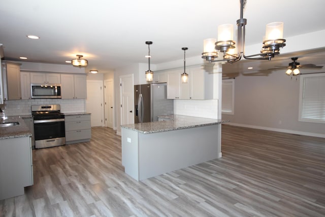 10141 S 33rd St, Vicksburg, MI 49097 - kitchen with appliances with stainless steel finishes, backsplash, gray cabinetry, a ceiling fan, and light stone counters