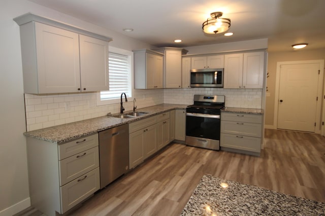 10141 S 33rd St, Vicksburg, MI 49097 - kitchen featuring appliances with stainless steel finishes, wood finished floors, gray cabinetry, light stone countertops, and backsplash
