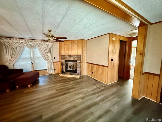 25654 Madison St, Novi, MI 48375 - living room featuring wooden walls, a ceiling fan, wood finished floors, a stone fireplace, and a wainscoted wall