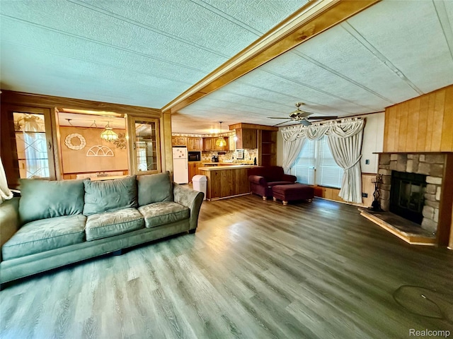 25654 Madison St, Novi, MI 48375 - living area with wood walls, wood finished floors, a stone fireplace, a ceiling fan, and a textured ceiling