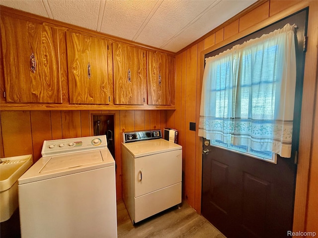 25654 Madison St, Novi, MI 48375 - laundry area featuring cabinet space, washer and clothes dryer, wood walls, light wood-style floors, and a textured ceiling