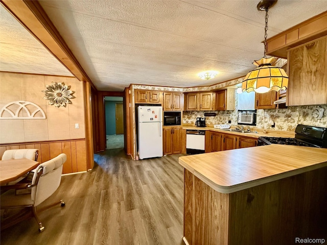 25654 Madison St, Novi, MI 48375 - kitchen with black appliances, brown cabinetry, light wood-type flooring, a peninsula, and wood walls