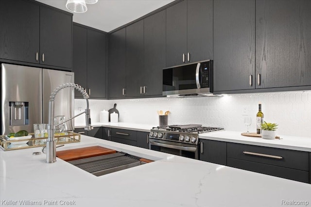 520 Kayser Ave, Birmingham, MI 48067 - kitchen with stainless steel appliances, light countertops, a sink, decorative backsplash, and dark cabinetry