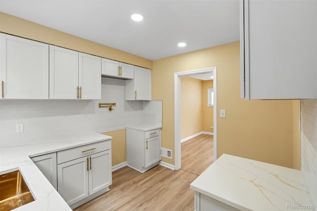 18696 Cherrylawn St, Detroit, MI 48221 - kitchen featuring light stone counters, backsplash, light wood-style flooring, white cabinetry, and recessed lighting