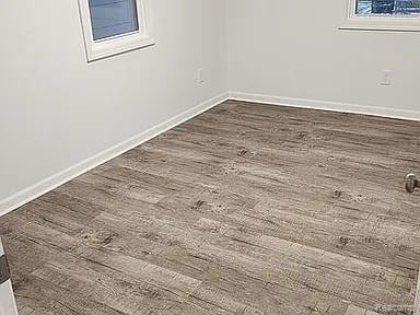 513 W Kilborn St, Lansing, MI 48906 - spare room featuring dark wood-style floors and baseboards