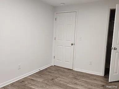 513 W Kilborn St, Lansing, MI 48906 - unfurnished bedroom featuring dark wood finished floors and baseboards