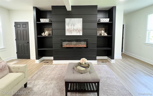 3461 Sheridan St, Detroit, MI 48214 - living room with light wood-type flooring, baseboards, built in shelves, and a glass covered fireplace