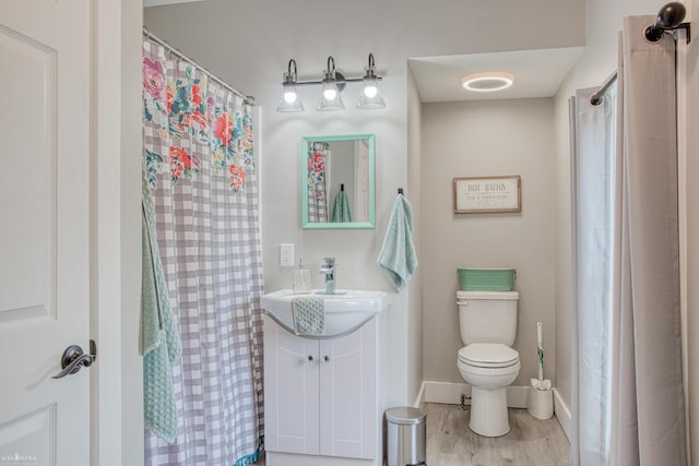 703 W Main St, Durand, MI 48429 - bathroom featuring vanity, toilet, baseboards, and wood finished floors