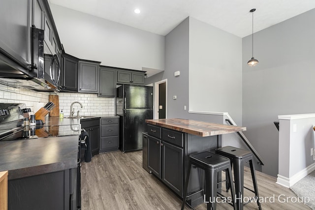 301 NW Xing Unit 25, Holland, MI 49423 - kitchen with wooden counters, black appliances, a breakfast bar, light wood-type flooring, and a sink