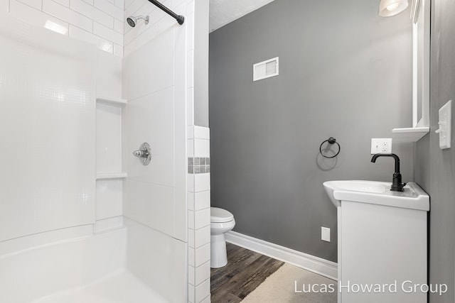 301 NW Xing Unit 25, Holland, MI 49423 - bathroom featuring toilet, a shower, wood finished floors, vanity, and baseboards