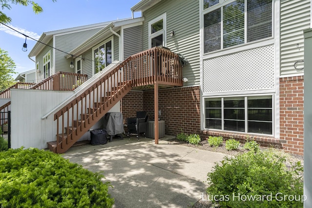 301 NW Xing Unit 25, Holland, MI 49423 - rear view of property with brick siding, a patio, stairs, and a deck