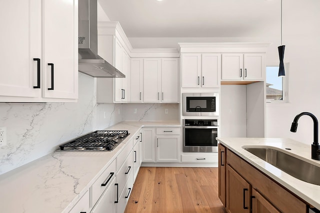 7467 Gramercy Cir W, Bloomfield, MI 48322 - kitchen featuring stainless steel appliances, wall chimney exhaust hood, a sink, light wood-style flooring, and white cabinetry