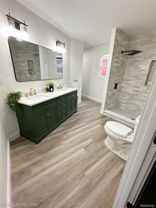3504 Townsend St, Detroit, MI 48214 - full bathroom featuring wood finished floors, double vanity, a tile shower, and toilet