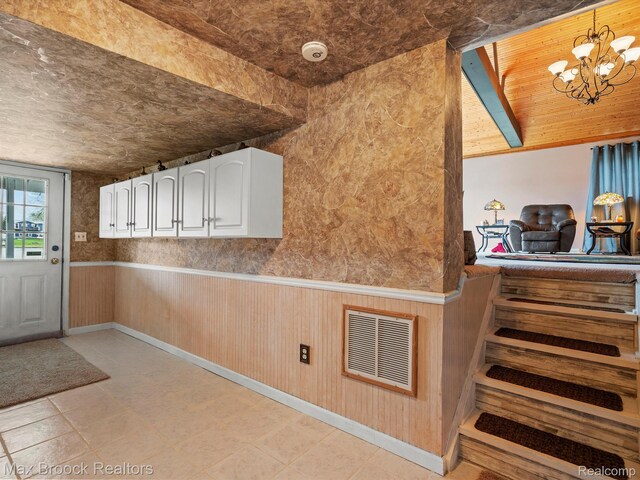 9431 Mandon Rd, White Lake, MI 48386 - kitchen featuring white cabinets, a chandelier, hanging light fixtures, and wainscoting