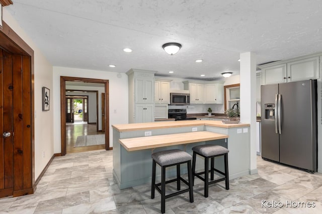 510 Division St, Big Rapids, MI 49307 - kitchen with wooden counters, stainless steel appliances, baseboards, a kitchen island, and a breakfast bar area