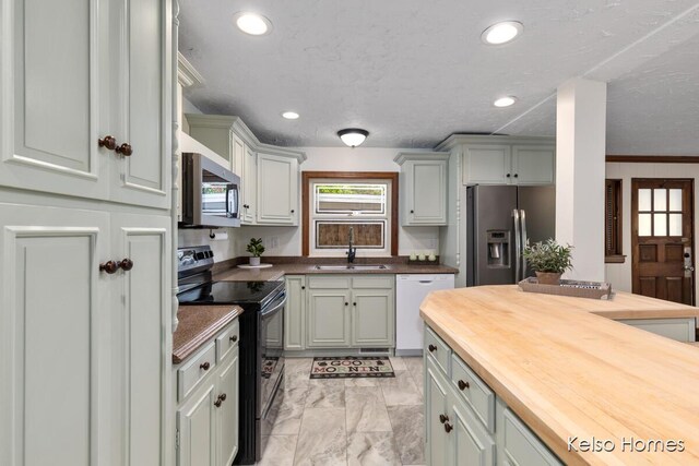 510 Division St, Big Rapids, MI 49307 - kitchen with appliances with stainless steel finishes, butcher block countertops, light marble finish floors, a sink, and recessed lighting
