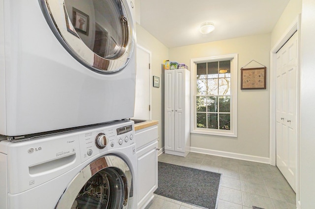 1336 Coventry Square Dr, Ann Arbor, MI 48103 - washroom with estacked washer and dryer, cabinet space, light tile patterned floors, and baseboards