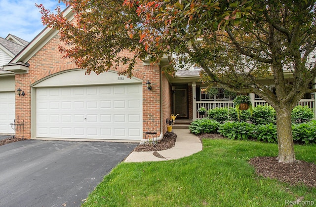 5886 Augusta Ln, Grand Blanc, MI 48439 - view of front of house with brick siding, asphalt driveway, an attached garage, covered porch, and a shingled roof