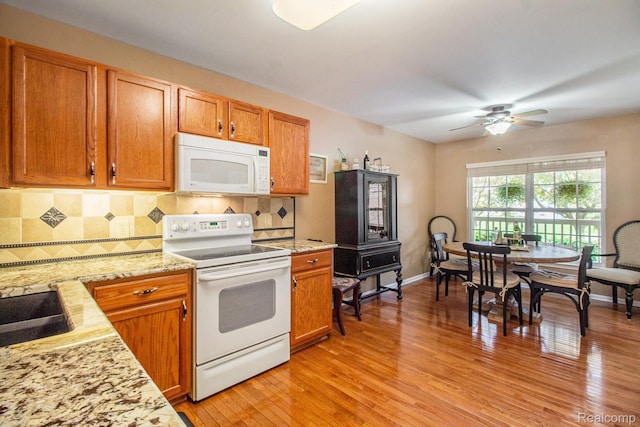 5886 Augusta Ln, Grand Blanc, MI 48439 - kitchen with white appliances, light wood-type flooring, a ceiling fan, decorative backsplash, and brown cabinets