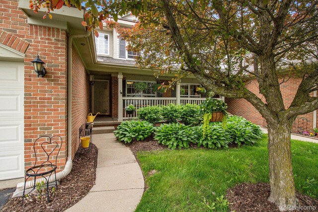 5886 Augusta Ln, Grand Blanc, MI 48439 - view of exterior entry with brick siding, a porch, and a garage