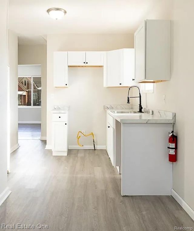 15827 Tracey St, Detroit, MI 48227 - kitchen with a sink, light wood-style flooring, light countertops, white cabinetry, and baseboards