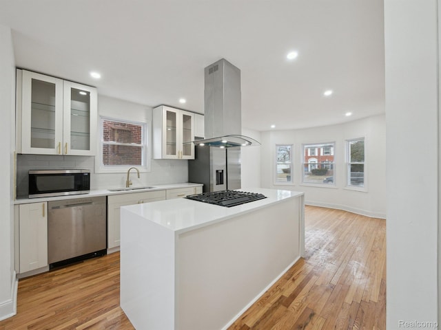 18212 Sorrento St, Detroit, MI 48235 - kitchen featuring appliances with stainless steel finishes, a sink, island exhaust hood, a kitchen island, and light wood-style flooring