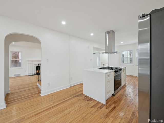 18212 Sorrento St, Detroit, MI 48235 - kitchen with island exhaust hood, stainless steel appliances, light wood finished floors, white cabinets, and light countertops