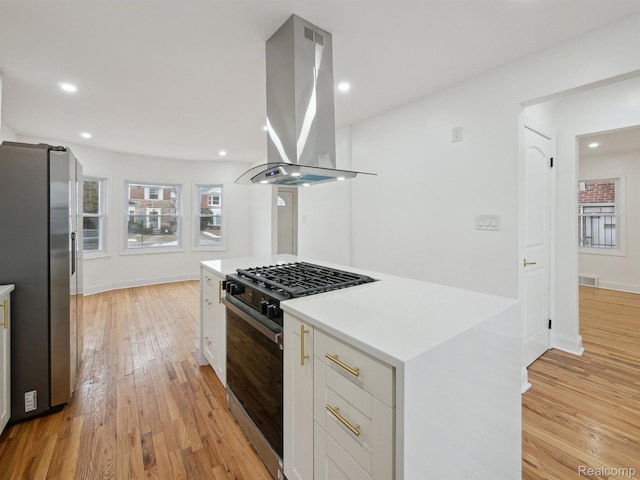 18212 Sorrento St, Detroit, MI 48235 - kitchen with black gas range, freestanding refrigerator, island range hood, white cabinetry, and light wood-style flooring