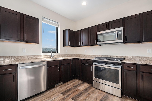 6016 Port View Dr SE, Grand Rapids, MI 49512 - kitchen featuring appliances with stainless steel finishes, a sink, dark wood-type flooring, dark brown cabinetry, and light stone countertops