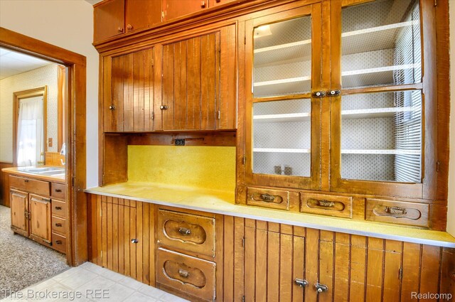 9425 W Saginaw Rd, Richville, MI 48758 - kitchen featuring light countertops, glass insert cabinets, light tile patterned flooring, and brown cabinetry