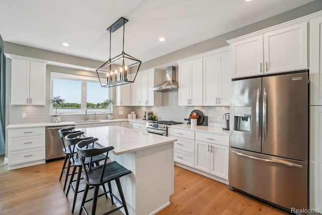 6652 Westminister St, Fenton, MI 48430 - kitchen featuring appliances with stainless steel finishes, wall chimney range hood, a sink, white cabinetry, and backsplash