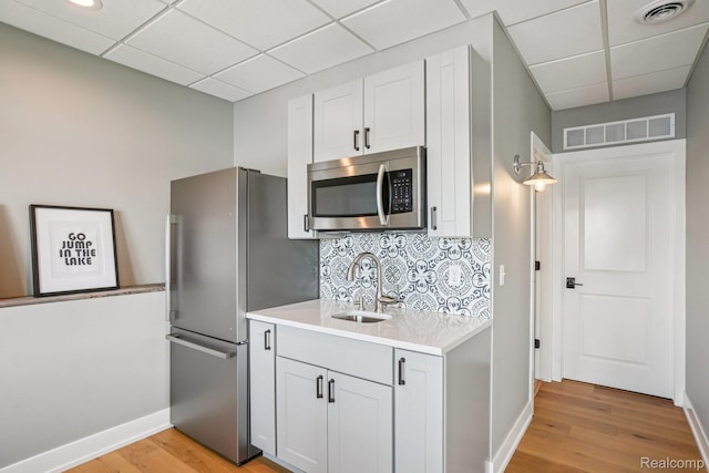6652 Westminister St, Fenton, MI 48430 - kitchen featuring appliances with stainless steel finishes, a sink, a drop ceiling, light countertops, and light wood-style floors