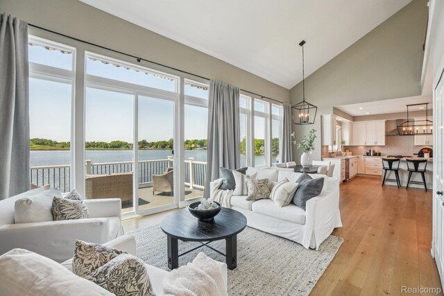6652 Westminister St, Fenton, MI 48430 - living room with a chandelier, high vaulted ceiling, light wood-type flooring, and a water view
