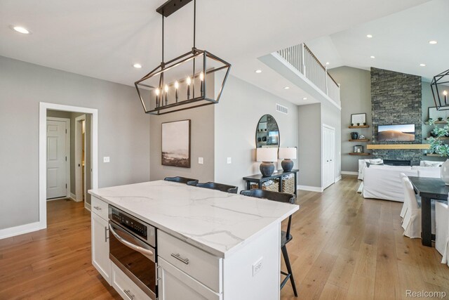 6652 Westminister St, Fenton, MI 48430 - kitchen featuring white cabinetry, a kitchen island, light wood-style floors, open floor plan, and a breakfast bar