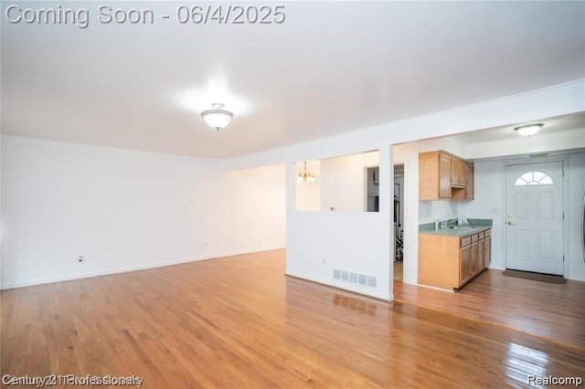 23060 Berdeno Ave, Hazel Park, MI 48030 - unfurnished living room featuring a sink, a chandelier, light wood-style floors, and baseboards