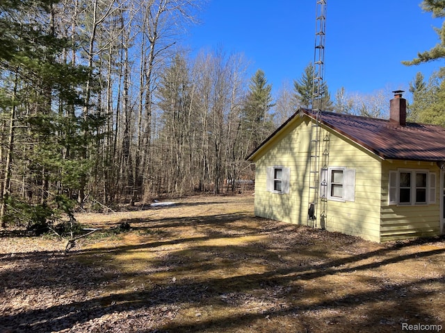 5400 Allen Rd, Alger, MI 48610 - view of home's exterior featuring a chimney and metal roof