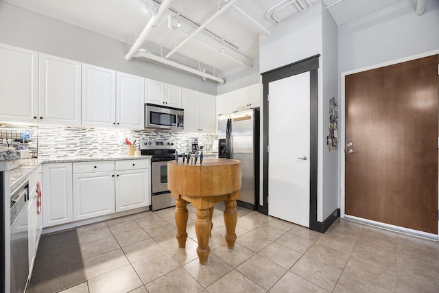 600 Broadway Ave NW Unit 117, Grand Rapids, MI 49504 - kitchen with appliances with stainless steel finishes, tasteful backsplash, white cabinetry, light stone counters, and a high ceiling