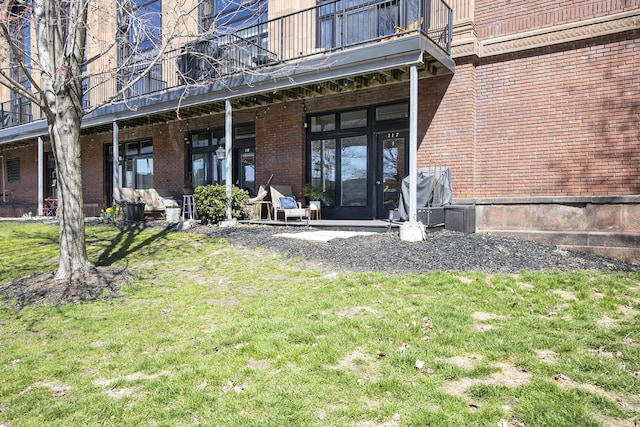 600 Broadway Ave NW Unit 117, Grand Rapids, MI 49504 - doorway to property with a balcony, brick siding, and a yard