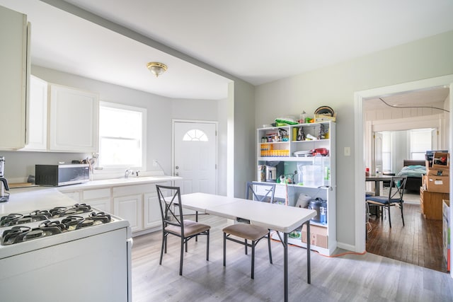 1007 Ionia Ave SW, Grand Rapids, MI 49507 - kitchen featuring white range with gas cooktop, stainless steel microwave, light wood-style flooring, white cabinets, and light countertops