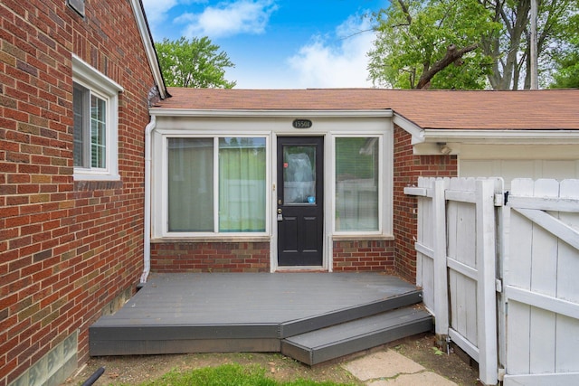 15501 E Jefferson Ave, Grosse Pointe Park, MI 48230 - view of exterior entry featuring roof with shingles, a deck, and brick siding