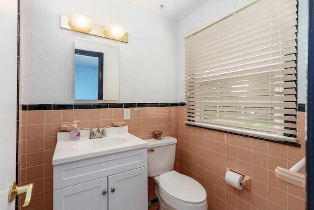15501 E Jefferson Ave, Grosse Pointe Park, MI 48230 - bathroom featuring tile walls, toilet, vanity, and wainscoting
